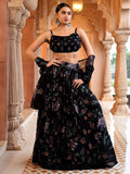 Woman in a black floral traditional outfit standing in an ornate architectural setting Glanzavi.