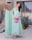 Woman in a light blue traditional outfit with pink floral details outdoors Glanzavi
