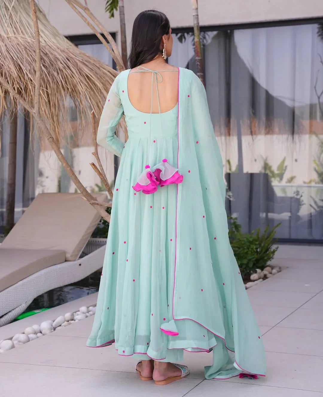 Woman in a light blue dress with pink accents standing outdoors Glanzavi