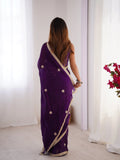 Woman wearing a purple saree with gold border in a minimal indoor setting Glanzavi