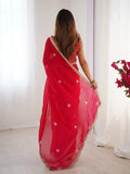 Woman wearing a red saree with white patterns in a minimalistic setting Glanzavi