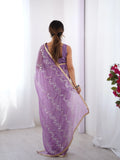 Woman wearing a purple saree with floral patterns in a minimal setting Glanzavi