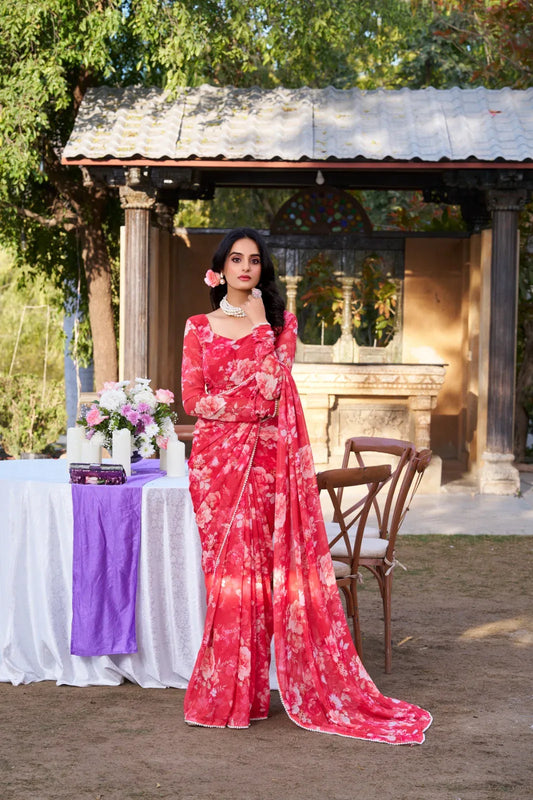 Woman in a red floral dress standing outdoors near a table with flowers and a purple tablecloth Glanzavi.