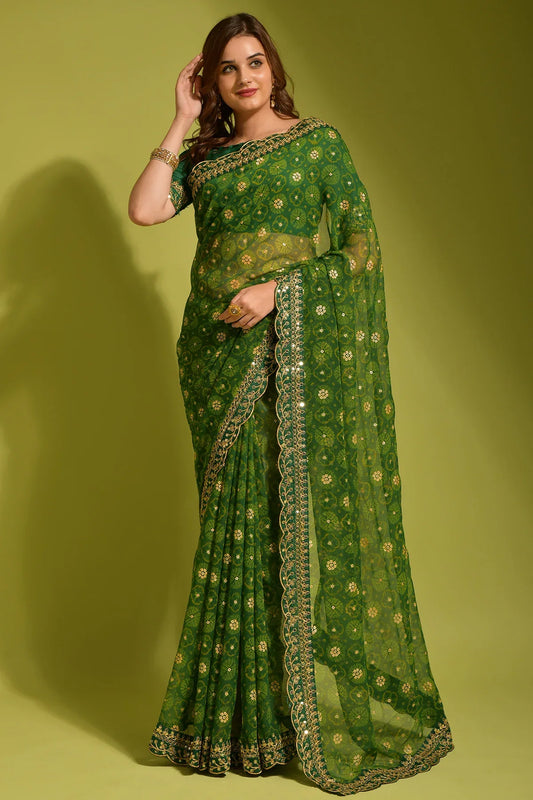Woman wearing a green saree with gold patterns on a yellow background Glanzavi