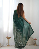 Woman holding a green saree in a minimalistic room with white curtains and decorative items Glanzavi