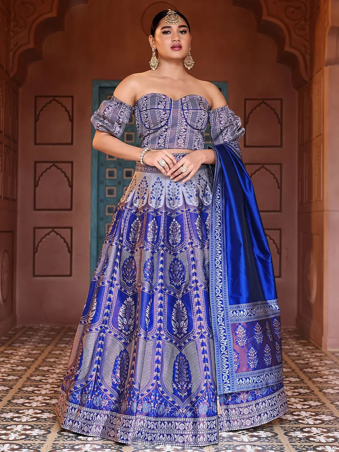 Woman in a traditional blue and silver embroidered outfit with a matching shawl indoors Glanzavi.