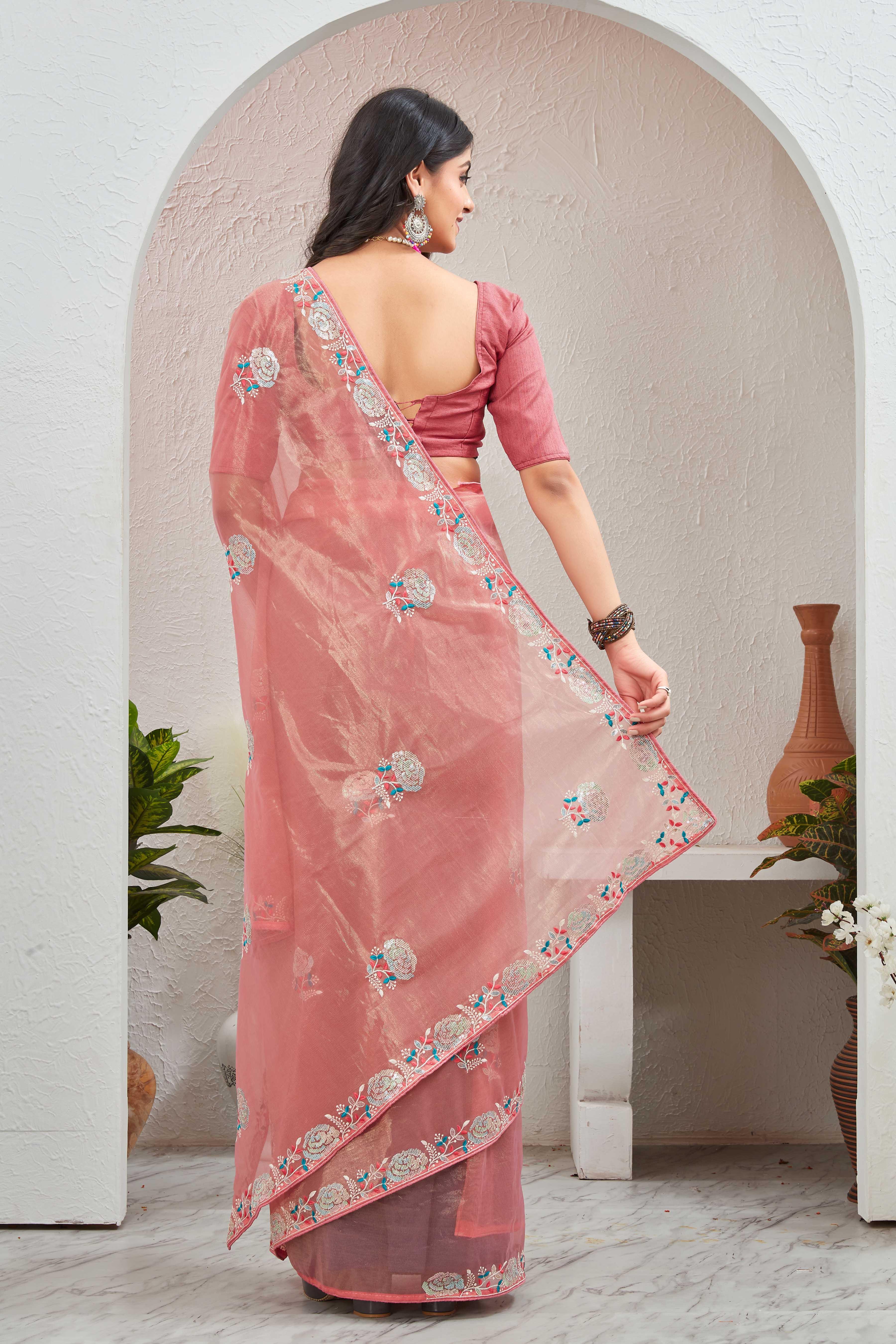 Woman wearing a pink saree with a floral border in an indoor setting Glanzavi.