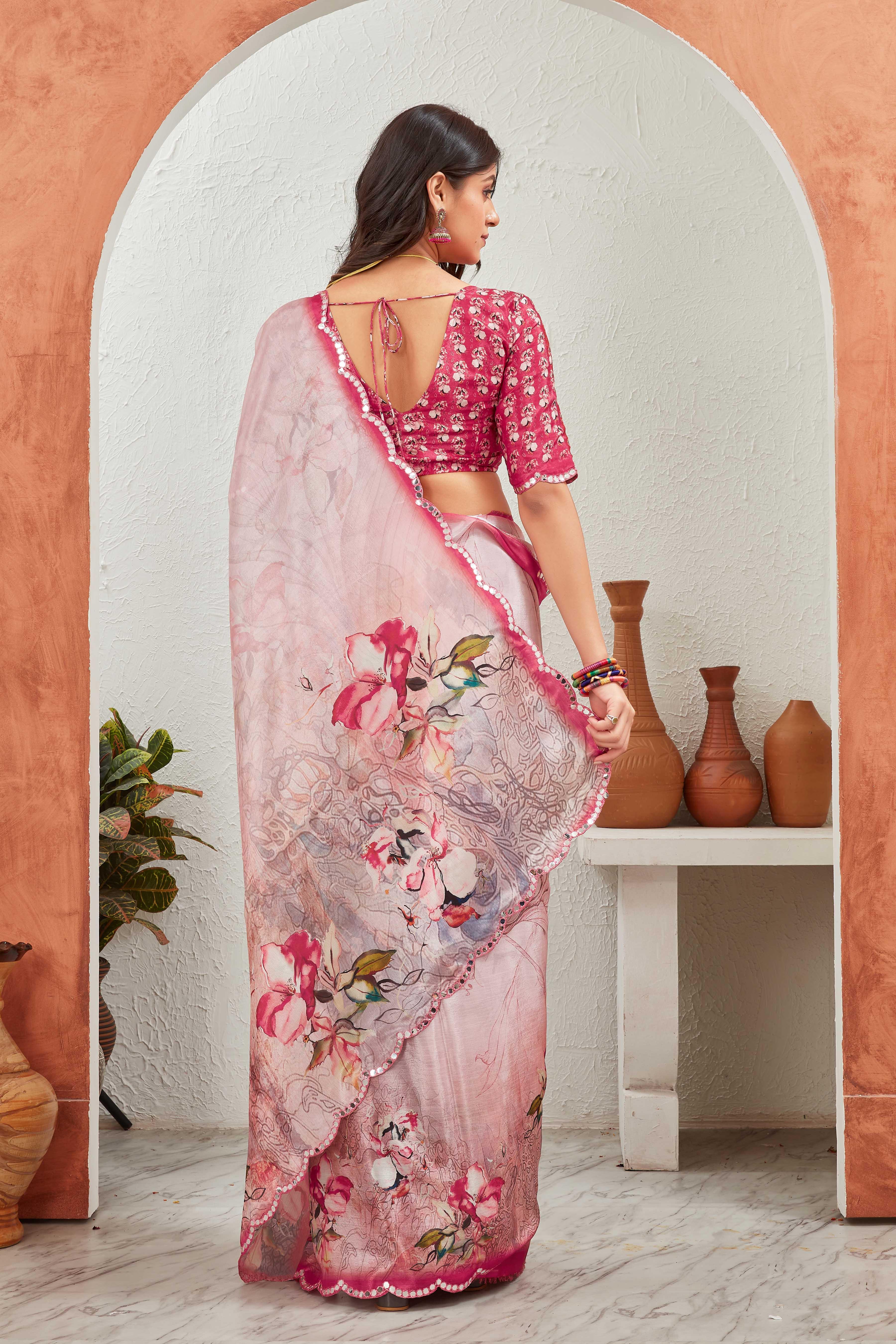 Woman in a pink floral saree standing in front of a decorative archway with vases Glanzavi