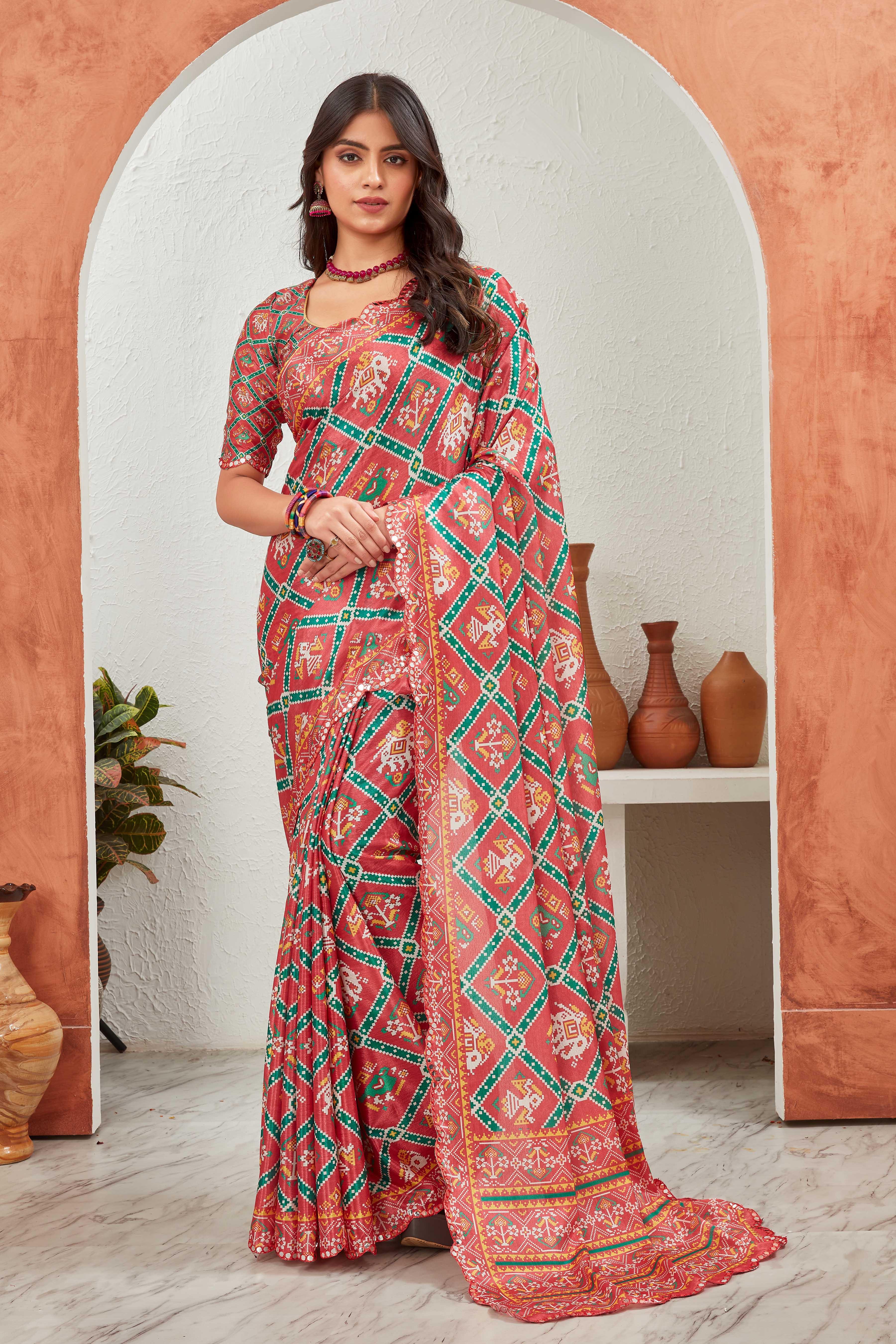Woman wearing a red and green patterned saree standing in a decorative archway Glanzavi.