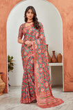 Woman wearing a red and green patterned saree standing in a decorative archway Glanzavi.