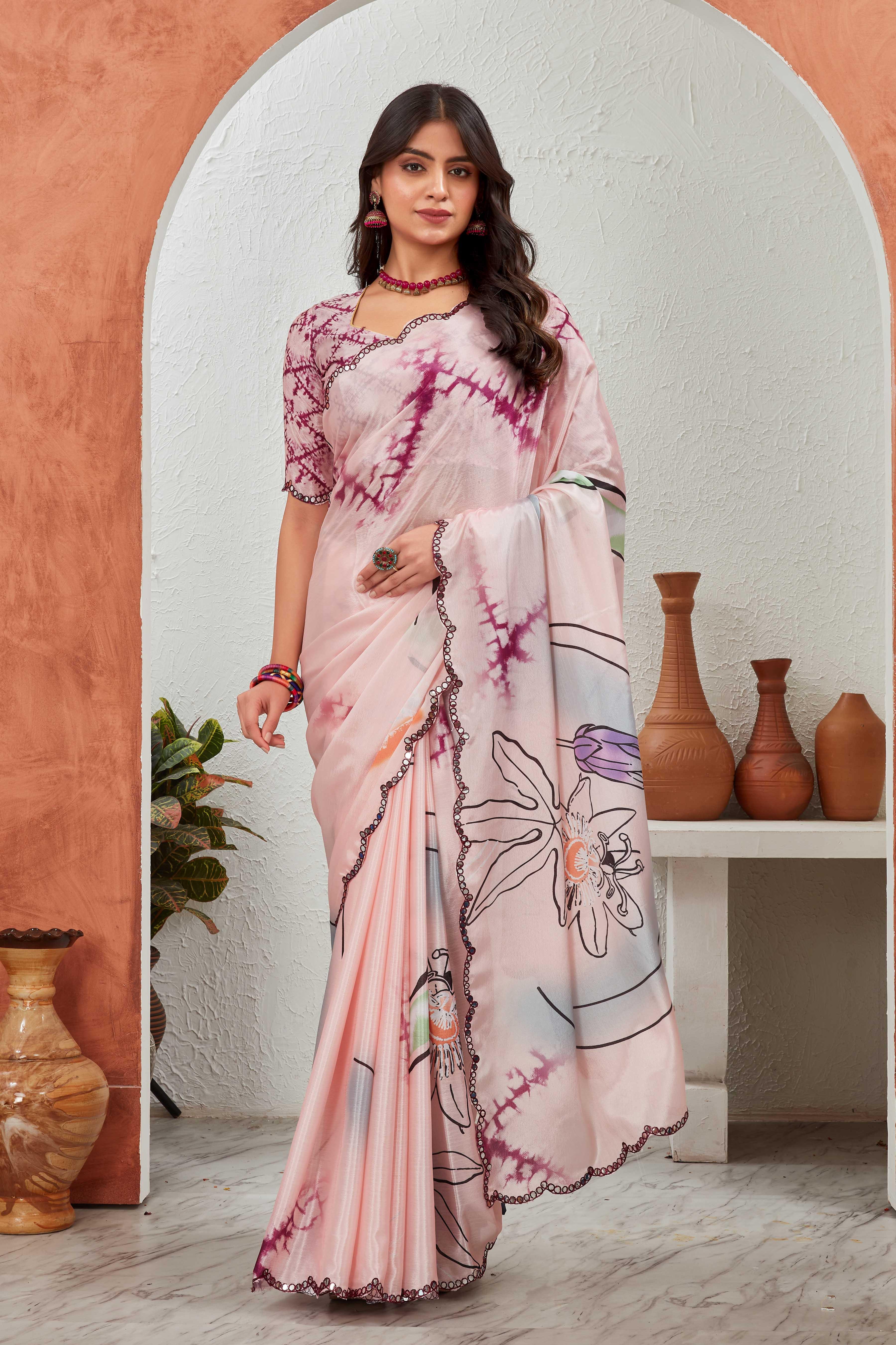 Woman wearing a pink saree with floral patterns in a decorative setting Glanzavi.