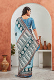 Woman wearing a traditional saree with a patterned design, standing in a room with decorative vases Glanzavi