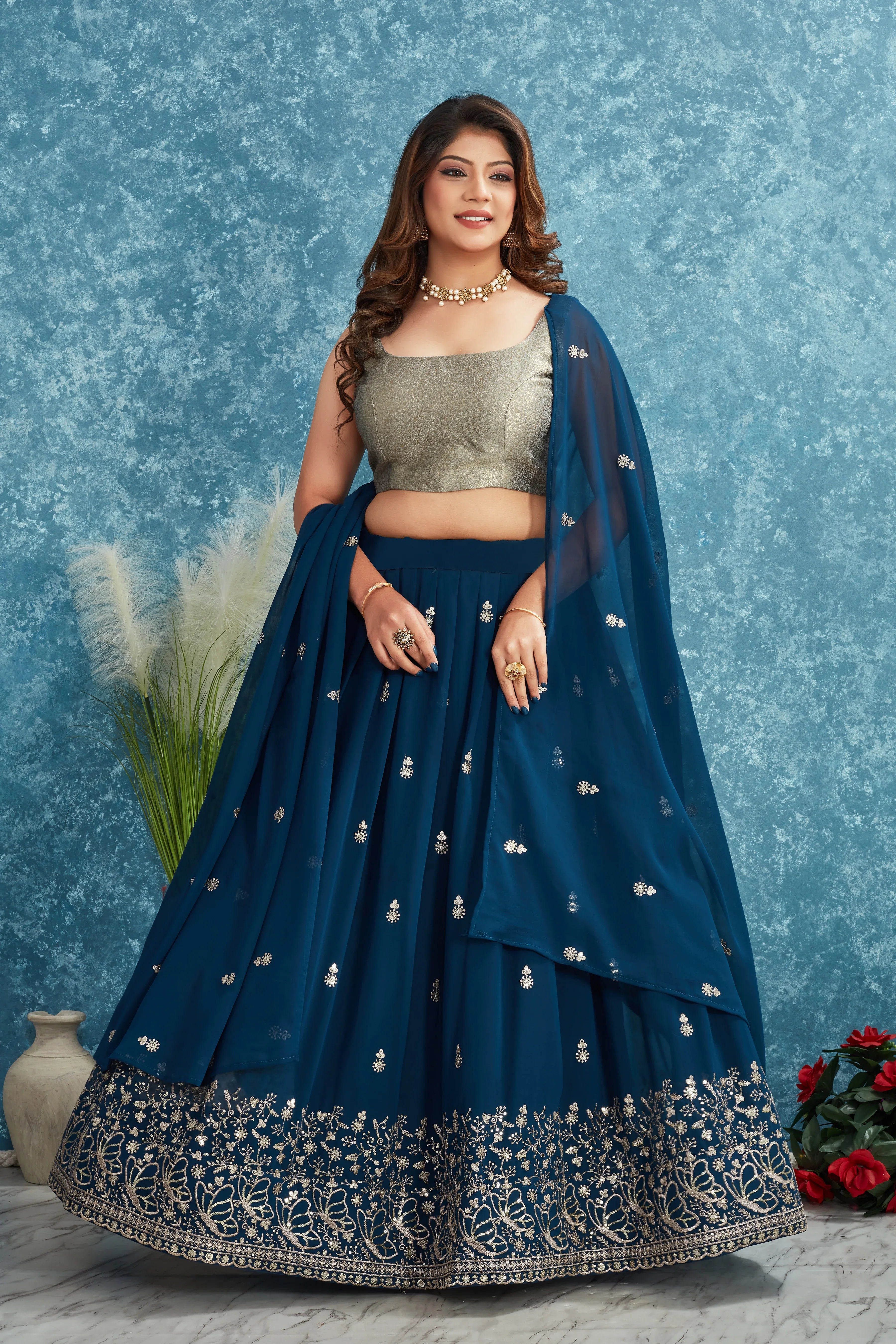 Woman wearing a blue and silver traditional outfit against a textured blue background Glanzavi