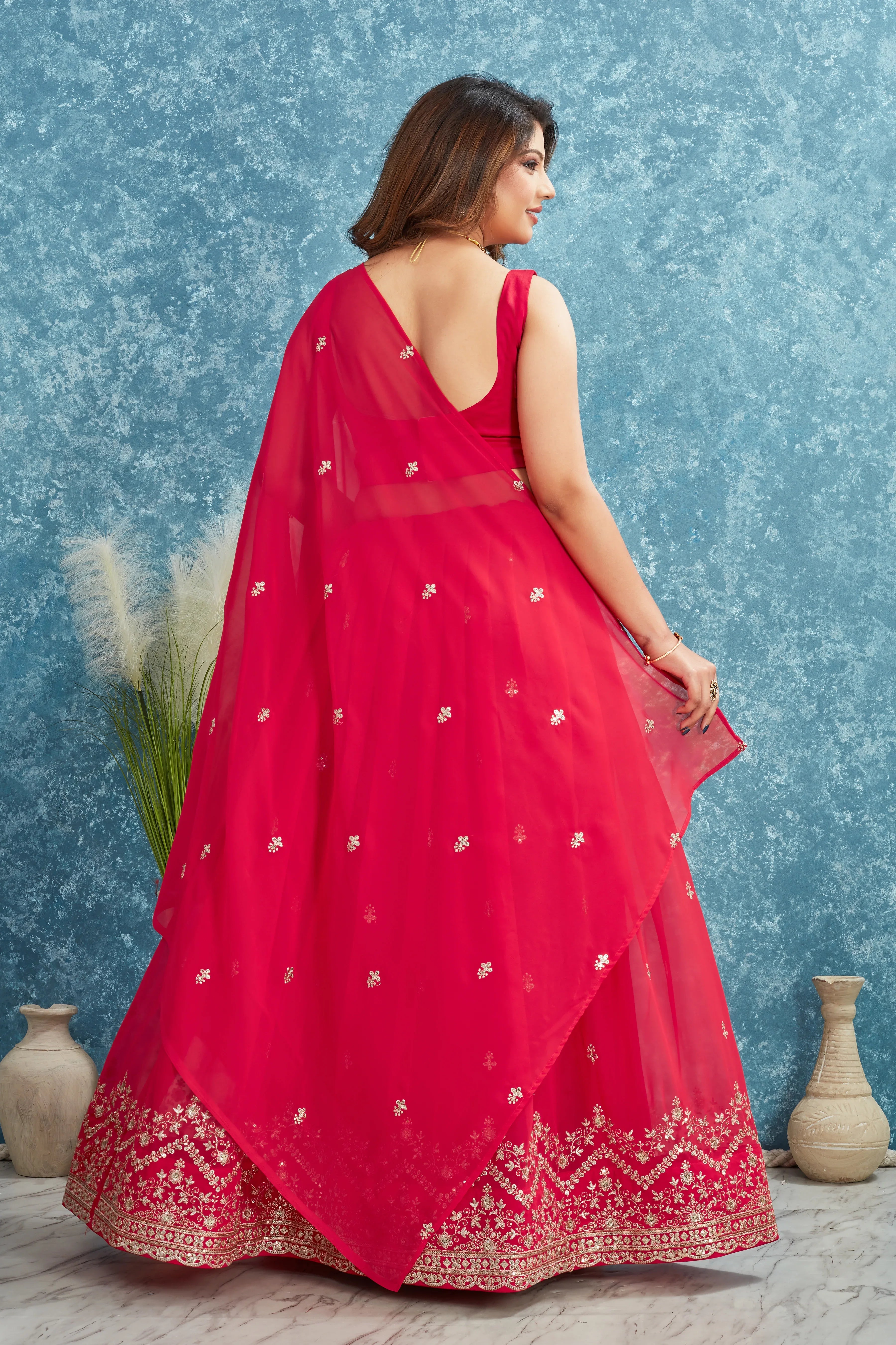 Woman wearing a red dress with white patterns against a blue textured wall Glanzavi