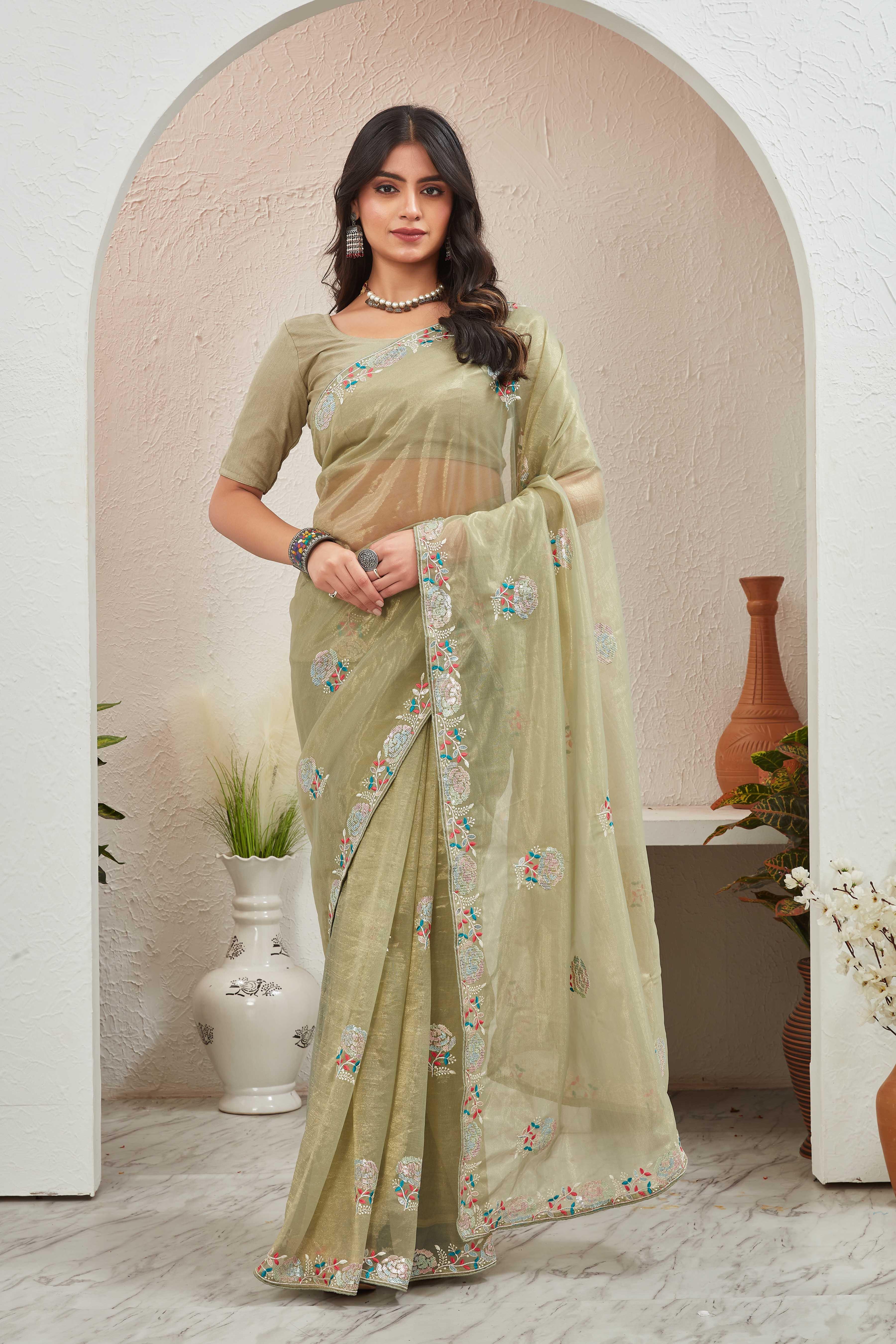 Woman wearing a light green saree with a floral border in an indoor setting Glanzavi.