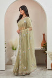 Woman wearing a light green saree with floral patterns in an indoor setting Glanzavi.