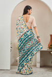 Woman wearing a colorful saree with a geometric pattern in a minimal indoor setting Glanzavi