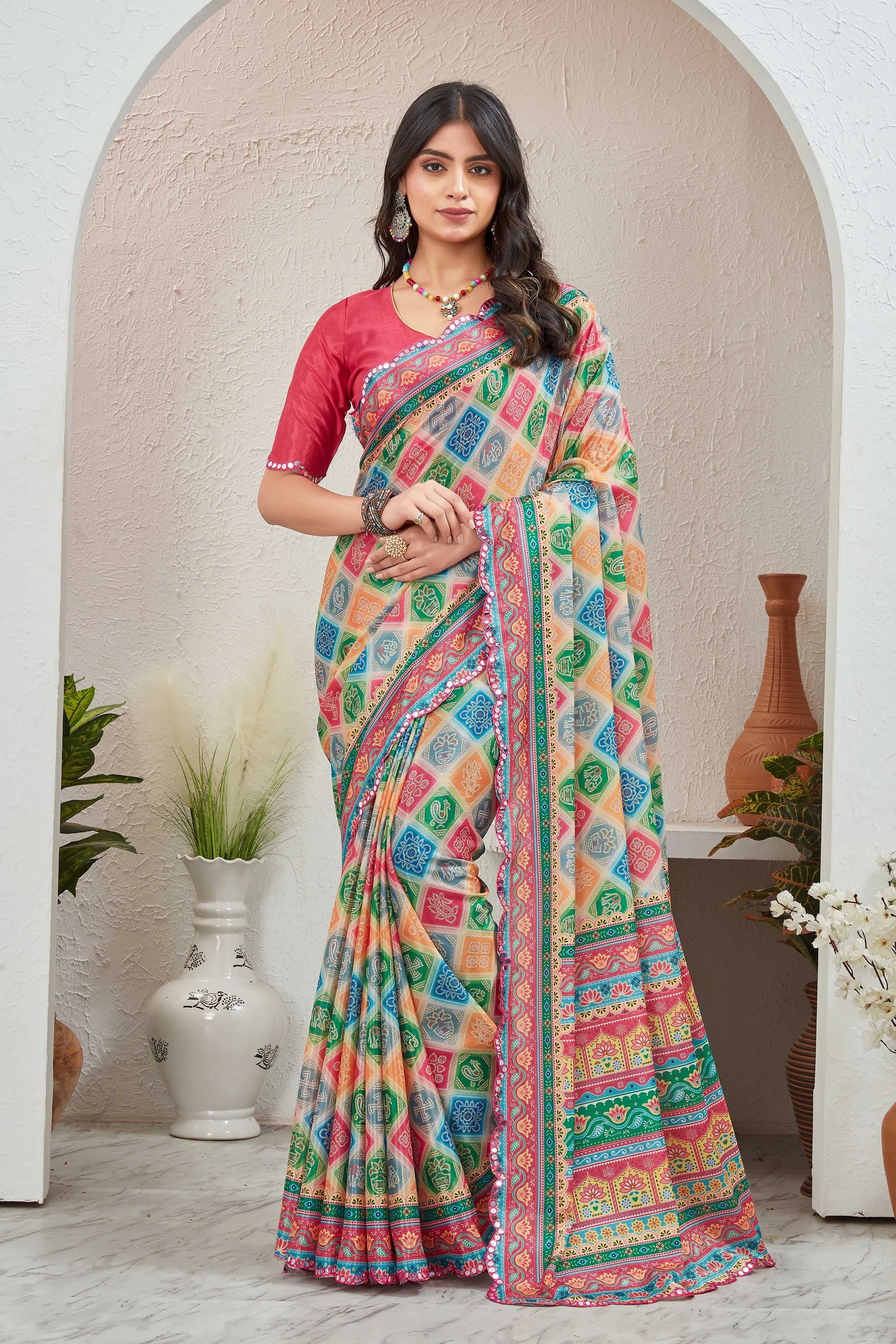 Woman wearing a colorful saree with a pink blouse in an indoor setting.
