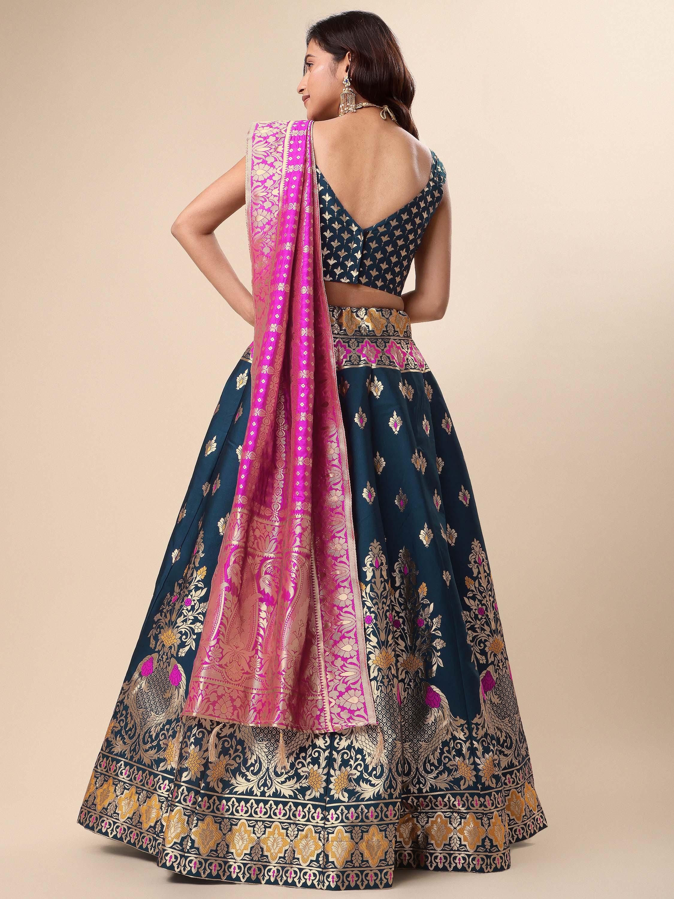 Woman wearing a traditional navy blue and pink embroidered lehenga with a beige background Glanzavi