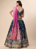 Woman wearing a traditional navy blue and pink embroidered lehenga with a beige background Glanzavi