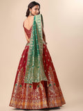 Red and gold embroidered traditional outfit with a green dupatta on a beige background Glanzavi