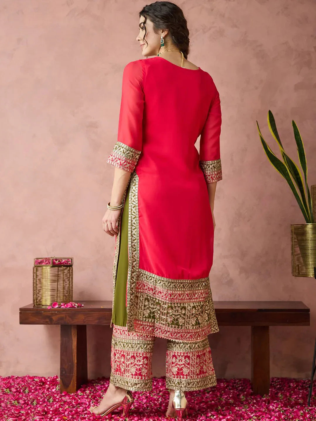 Woman wearing a red kurta with green and pink patterns in a decorative setting Glanzavi