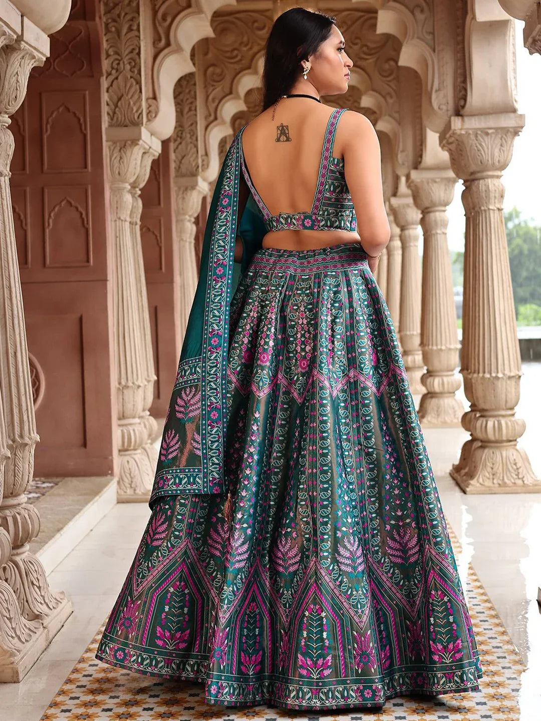 Woman in a traditional patterned outfit standing in an architectural setting Glanzavi