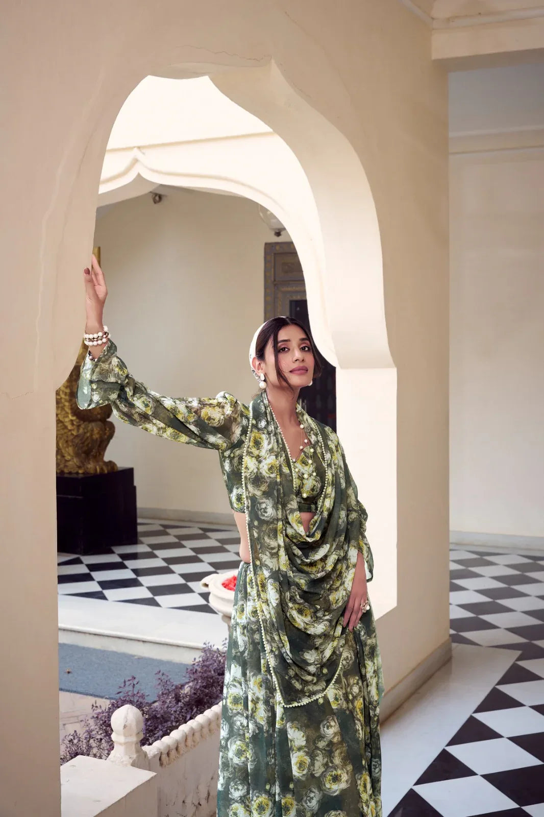 Woman in a floral dress standing in a room with checkered floor and archway Glanzavi.