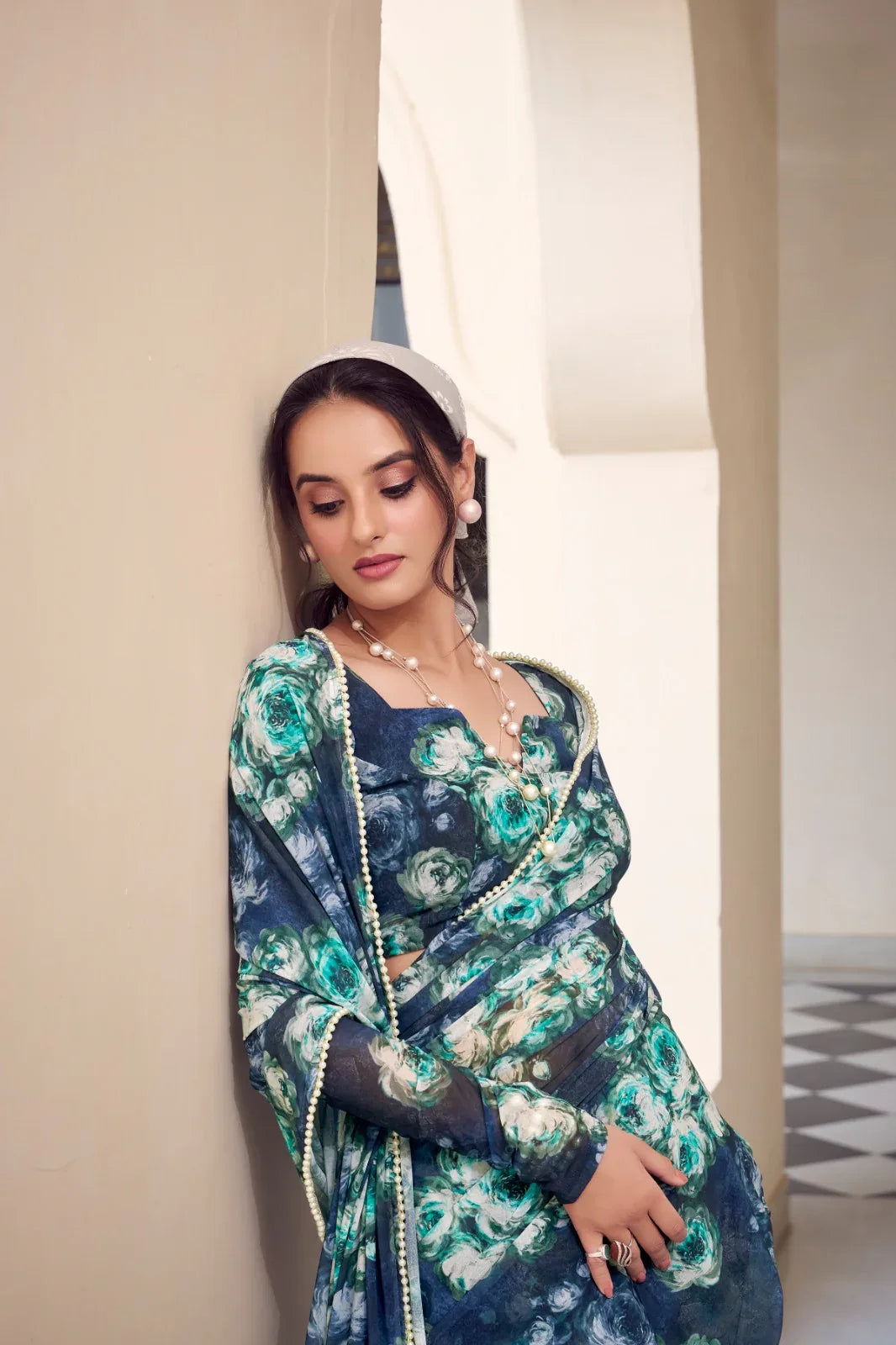 Woman in a floral dress standing against a neutral wall Glanzavi.