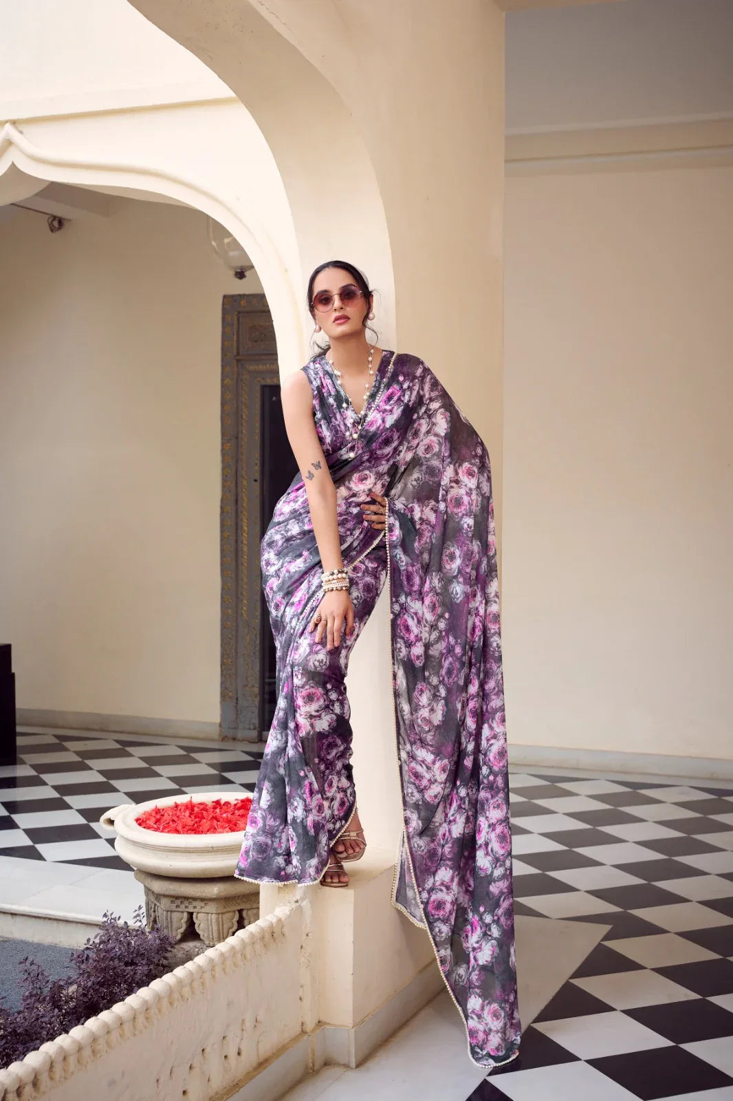 Woman in a floral outfit standing in an elegant interior setting with checkered floor Glanzavi.