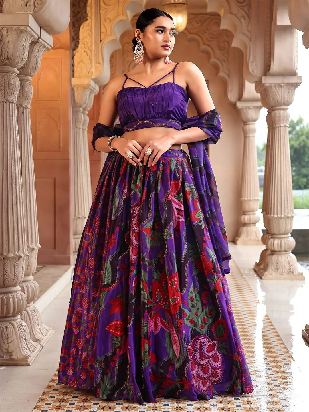 Woman in a purple and red patterned traditional outfit standing in an ornate architectural setting Glanzavi.