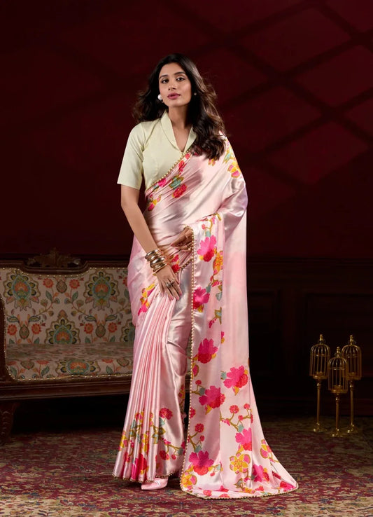 Woman in a pink floral saree standing in an elegant room with a dark background Glanzavi