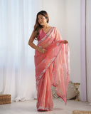 Woman wearing a light Peach saree with floral patterns against a white background Glanzavi