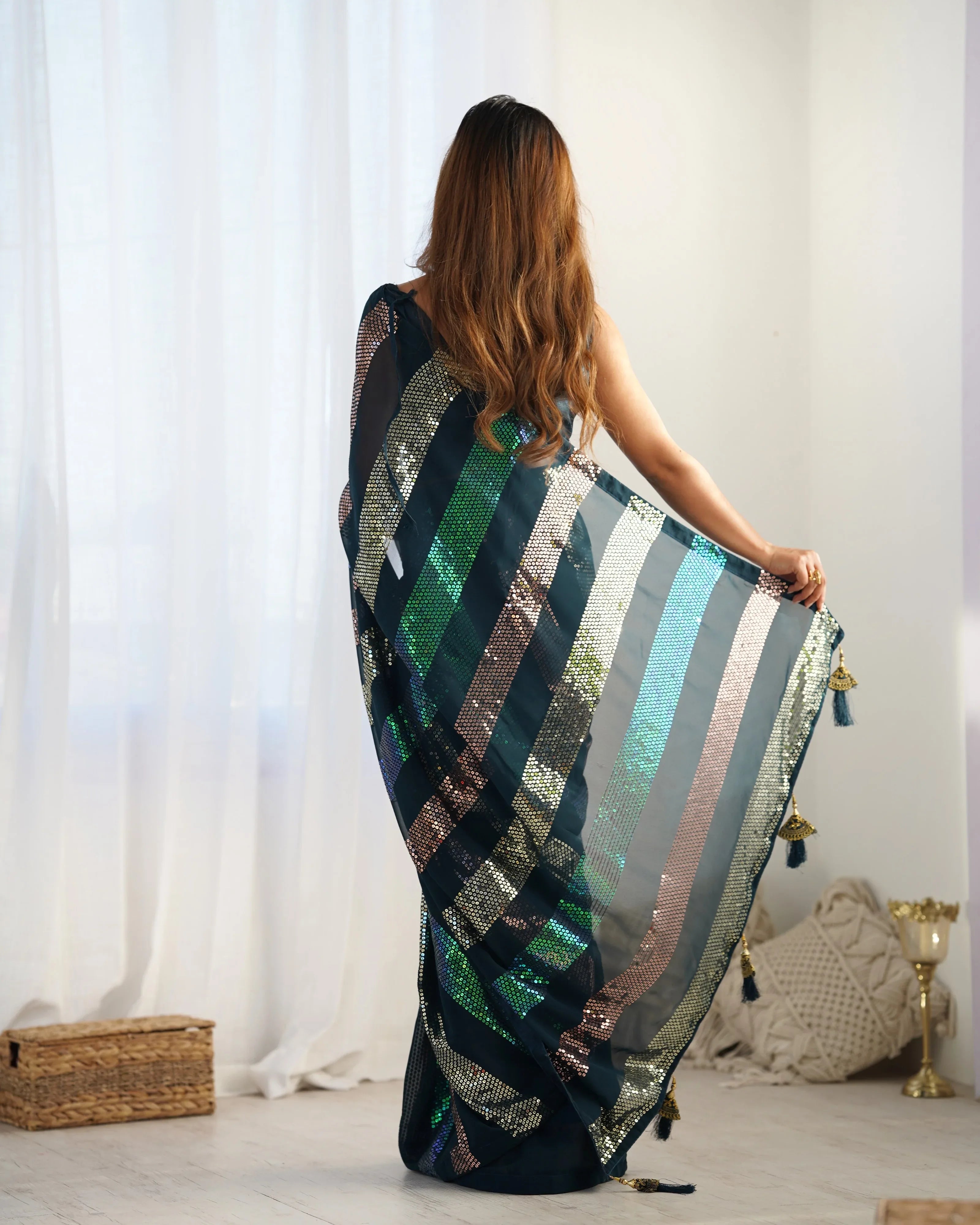 Woman holding a colorful striped scarf in a room with white curtains and a wooden box Glanzavi