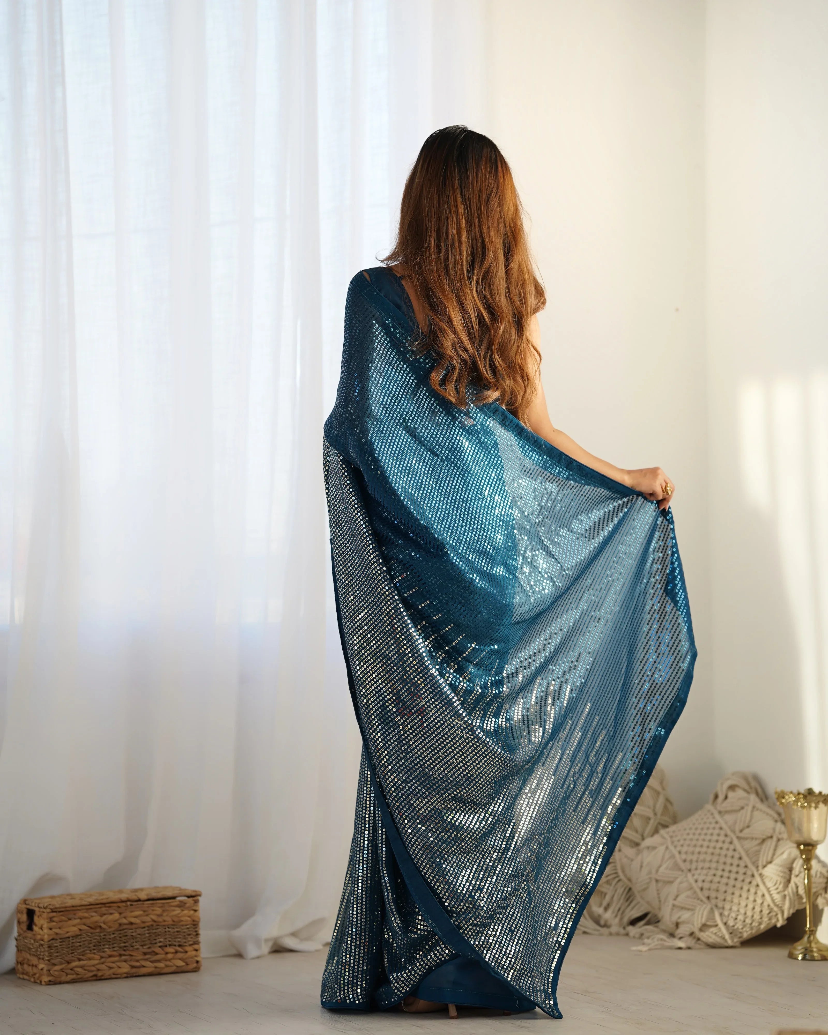 Woman holding a blue shawl in front of white curtains Glanzavi