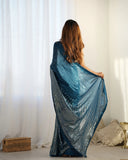 Woman holding a blue shawl in front of white curtains Glanzavi