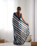 Woman wearing a blue and beige striped dress against a white curtain background Glanzavi
