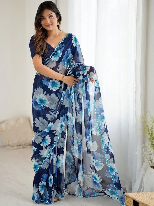 Woman wearing a blue floral saree in a bright room Glanzavi.