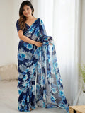 Woman wearing a blue floral saree in a bright room Glanzavi.