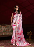 Woman wearing a white saree with pink floral patterns in an elegant indoor setting Glanzavi.