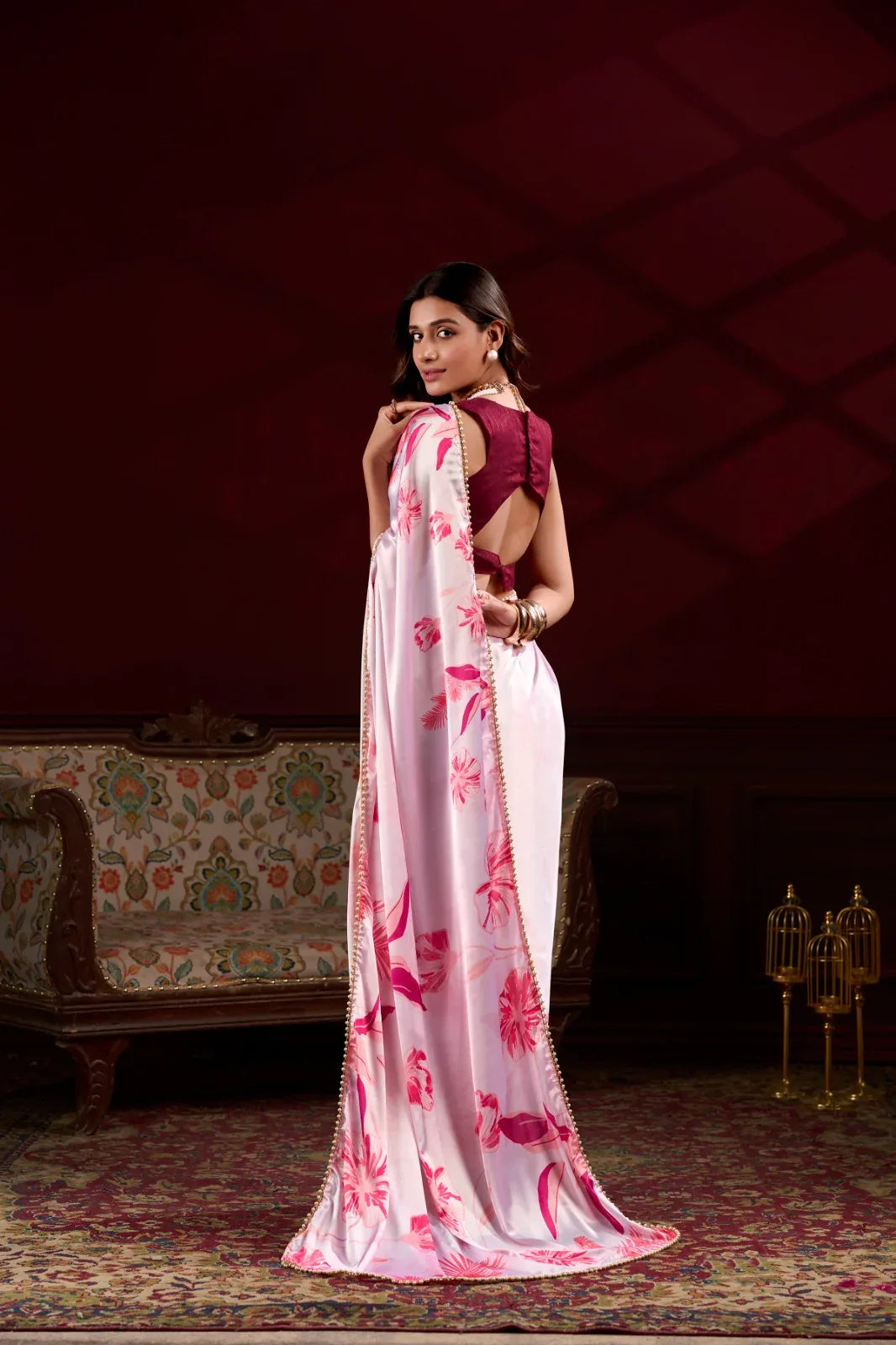 Woman in a white saree with pink floral patterns in an elegant room Glanzavi.