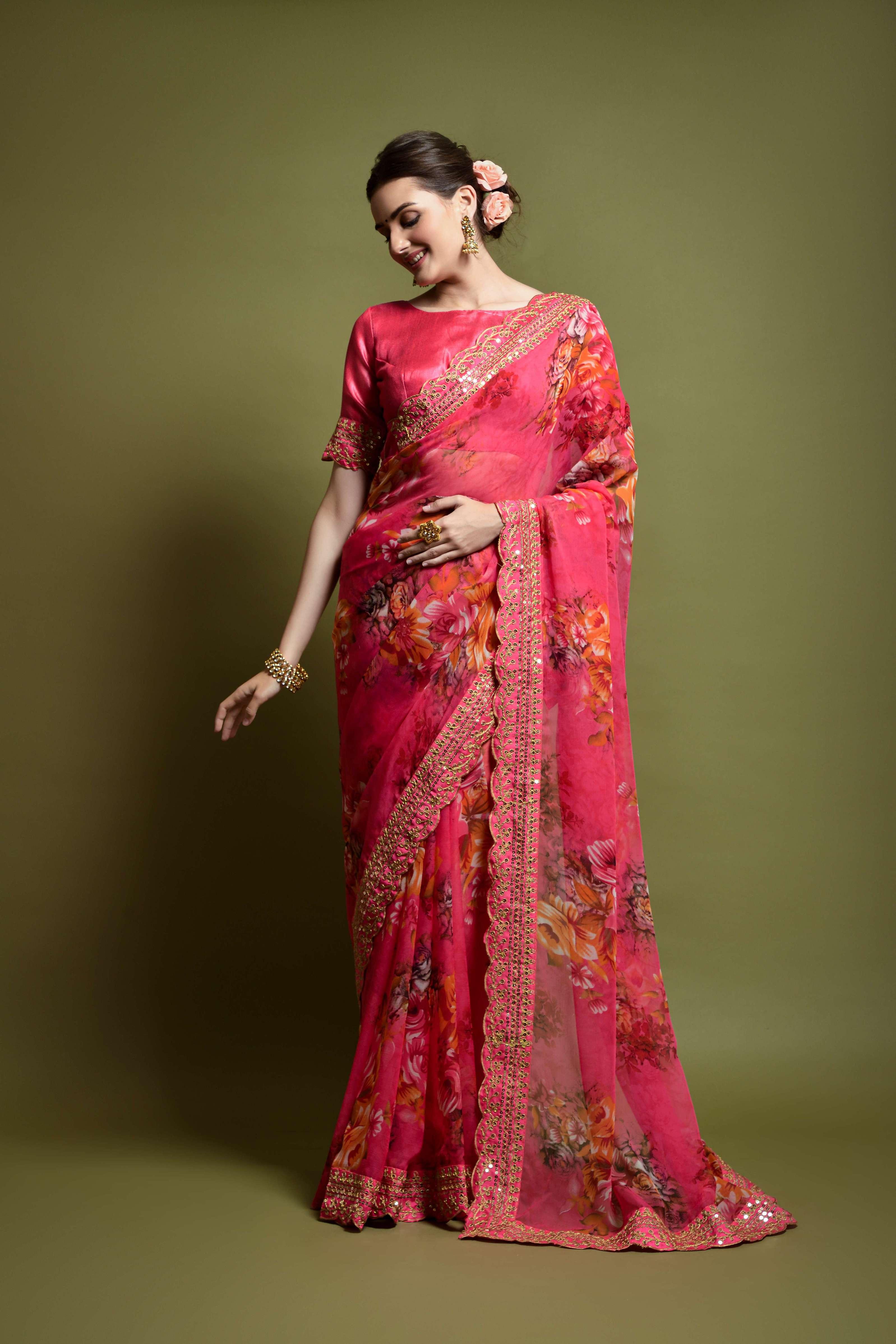Woman wearing a vibrant pink saree with floral patterns on a green background Glanzavi