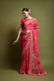 Woman wearing a vibrant pink saree with floral patterns on a green background Glanzavi