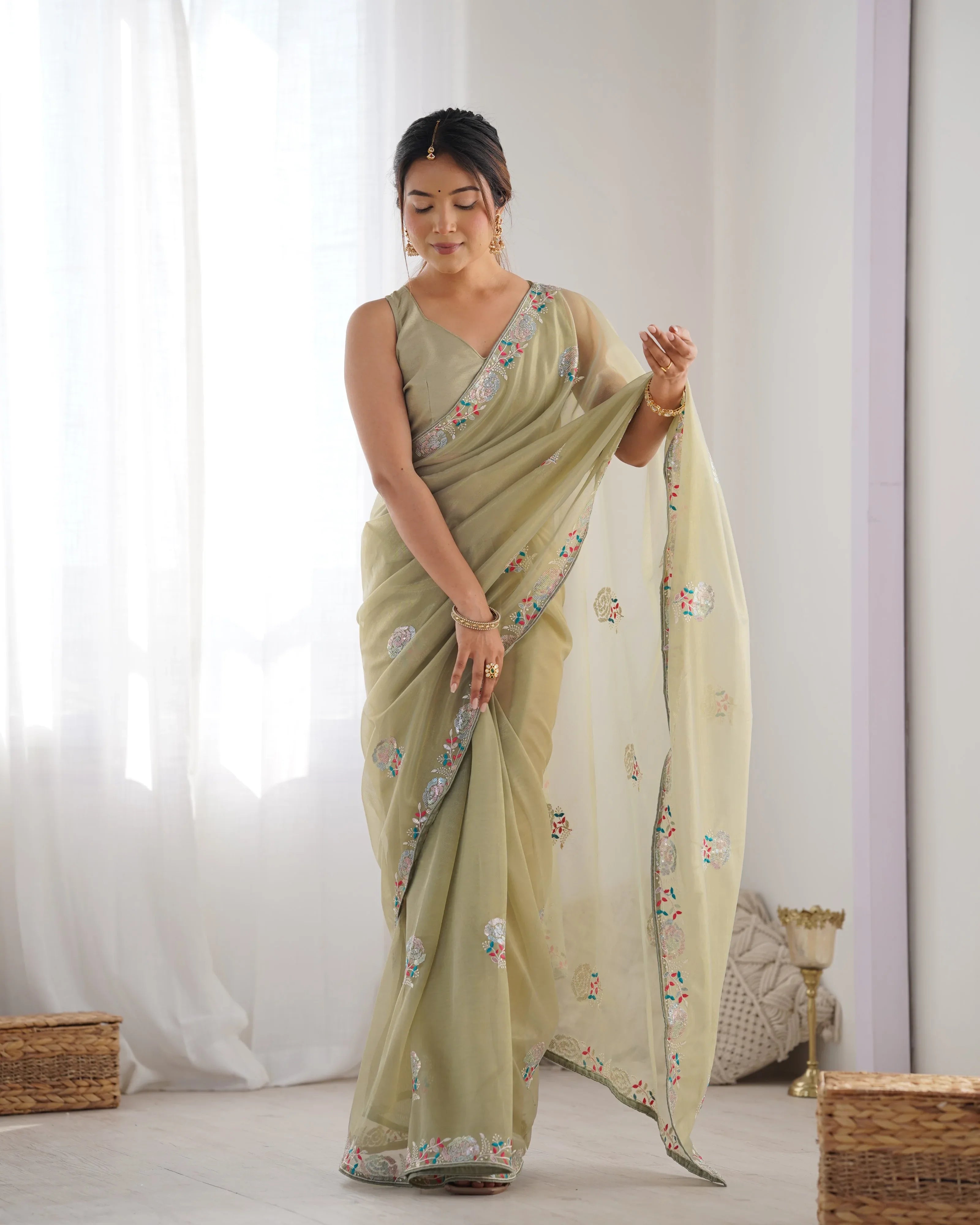Woman wearing a light green saree with floral patterns in a minimalistic setting Glanzavi