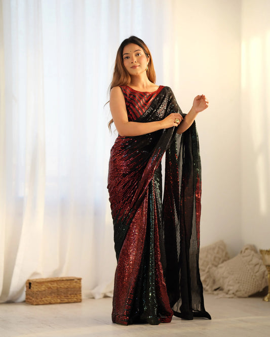 A woman posing in a red and green ombre sequin saree with a black pallu, featuring all-over linear sequin embellishment, paired with a matching sleeveless blouse Glanzavi