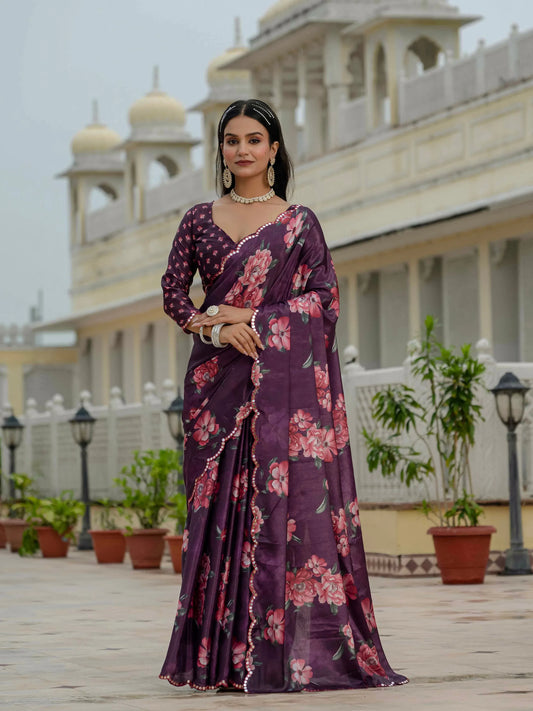Woman in a purple floral saree standing in front of a building with architectural details Glanzavi.