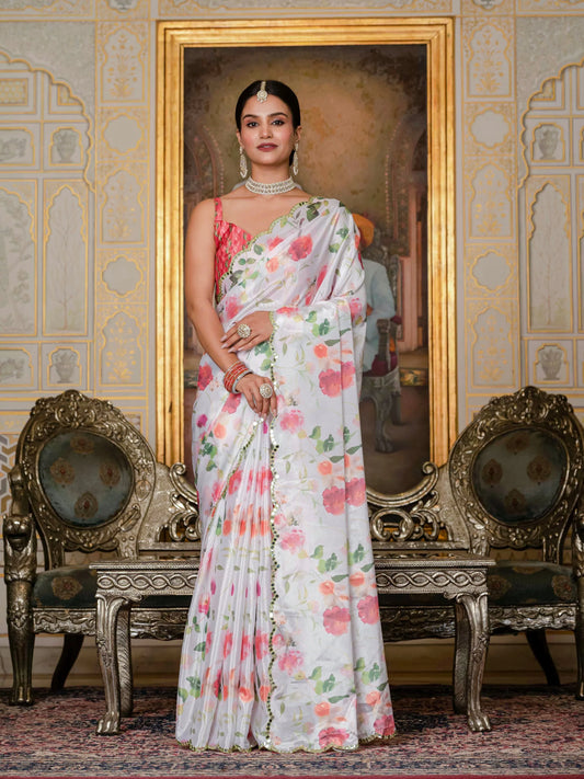 Woman in a floral saree standing in front of a decorative wall with ornate chairs Glanzavi.