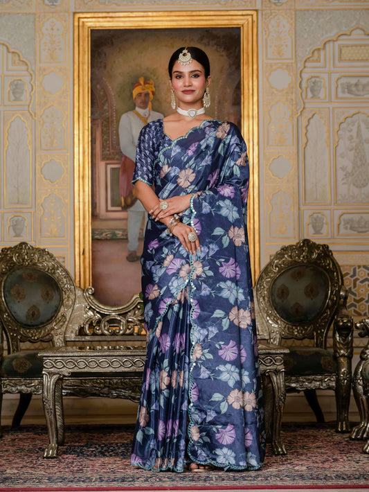 Woman in a blue floral saree standing in an ornate room with decorative chairs and wall art Glanzavi.