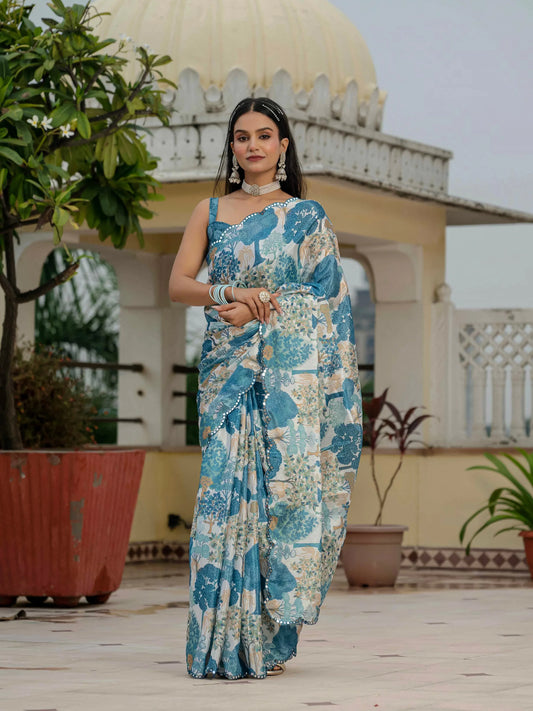Woman in a blue floral saree standing in front of a traditional building with dome and arches Glanzavi.
