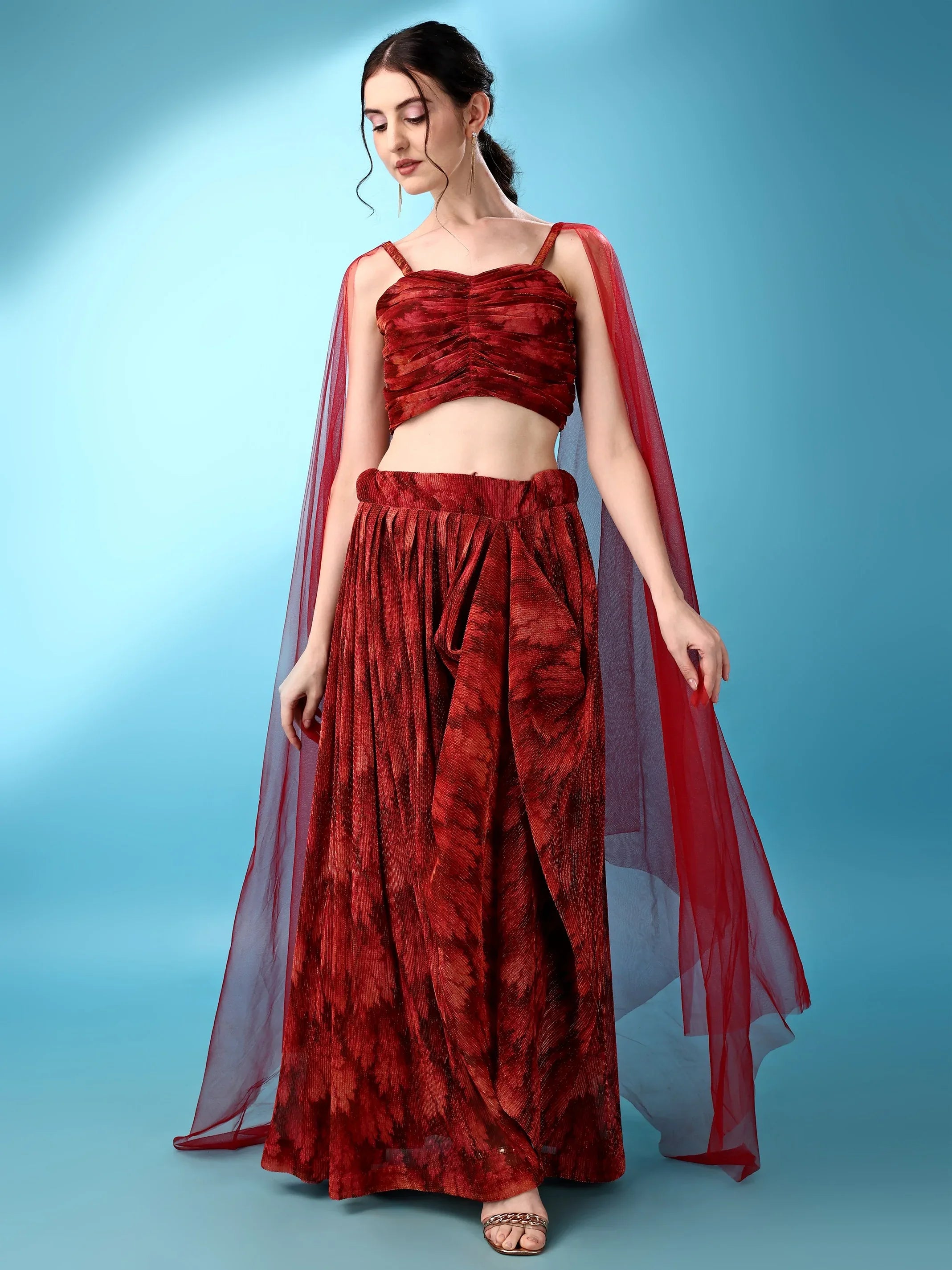 Woman wearing a red floral outfit with a sheer dupatta against a blue background Glanzavi